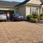 Driveway pavers installation in a front yard with a parked car and house.